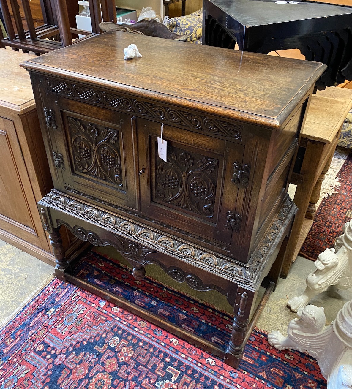 A 1920's Jacobean Revival carved oak cabinet on stand, width 91cm, depth 49cm, height 100cm